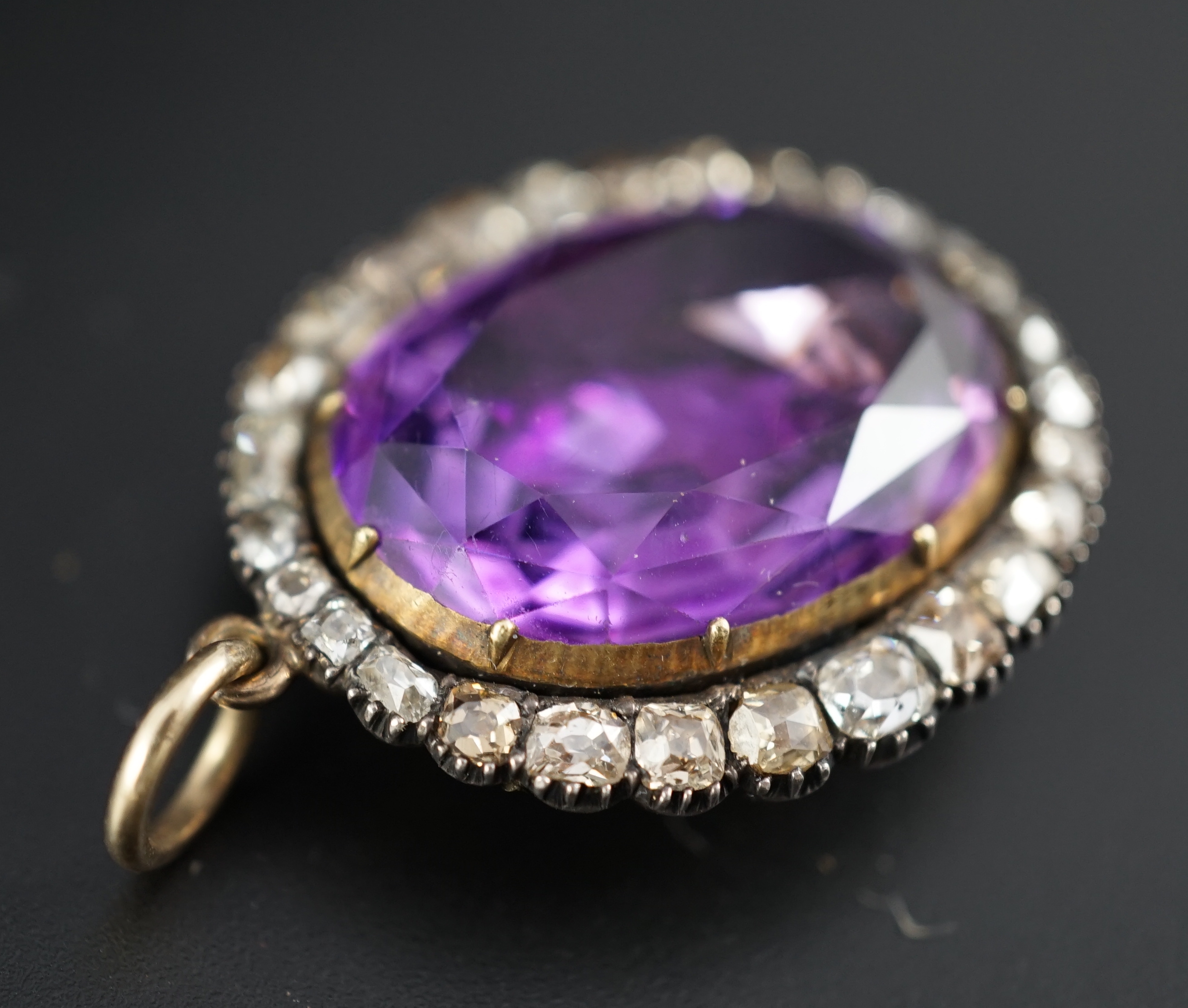 An early 19th century, gold and oval cut foil backed amethyst set pendant, with old cut diamond set border and closed back setting